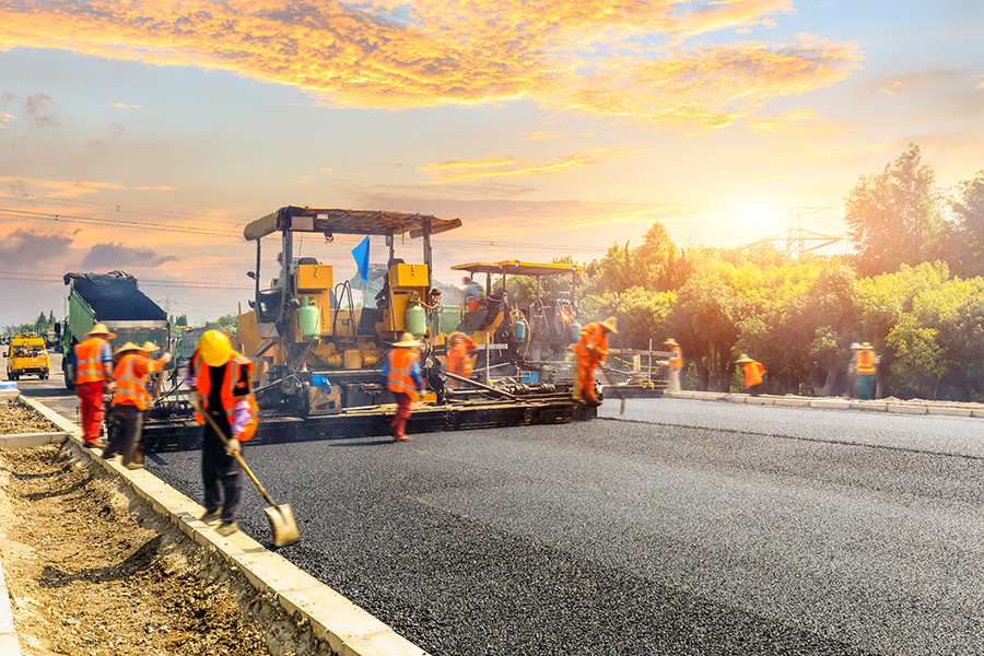 Construction site is laying new asphalt road pavement,road construction workers and road construction machinery scene.